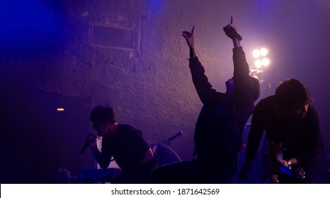 Silhouette Of Rock Band With Vocalist Show Hands Raised Up Performing On Stage, Rock Concert Show Set Up.