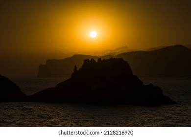 Silhouette Of Rocks In The Sea And The Island In The Setting Sun. Malgrat, Mallorca. Positive Energy And Warm Colors.