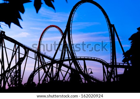 silhouette of a roller coaster at a blue sunset during a fun fair at entertainment thematic park