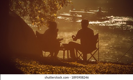 silhouette romantic couple on camping by the river, outdoors cople camping, Happy outdoor lifestyle. Young couple enjoying a day relaxing in the park