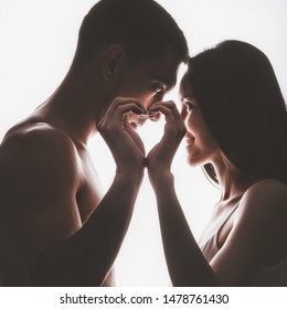 Silhouette Romantic Portrait Of Young Couple In Love, Man And Woman Face To Face, In Foreground Hands Folded Into Heart, Small Depth Of Field