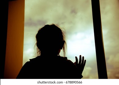 Silhouette Sad Little Girl In Room And Looking Out The Window