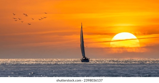 Silhouette of a sailboat sailing towards the sun at sunset - Powered by Shutterstock