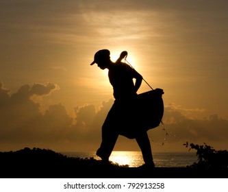 Silhouette of a salt farmer carrying homemade yoked baskets to collect sea water as part of the natural gourmet salt production process, Kasumba, Bali - Shutterstock ID 792913258