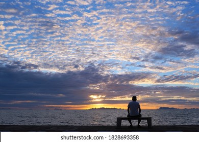 Silhouette of senior man sitting alone on the bench in front of the sea in the evening, Man sitting  on the bench and watching sunset over the sea at Samui Thailand - Powered by Shutterstock