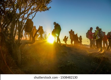 Silhouette shadow of separate groups of travelers with sun ray background after observing sunrise on mountain, Bromo, East Java, Indonesia, July 2019