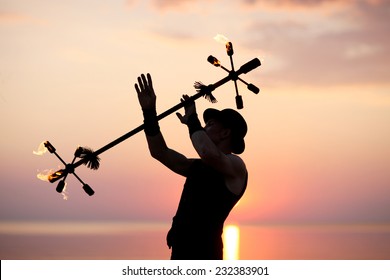 Silhouette Of Showman Juggling With Fire Baton