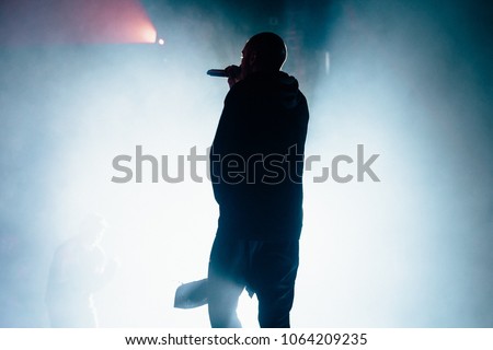 Silhouette of a singer on the stag. Silhouette of a rapper with a towel. Bright background.  