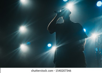 A silhouette of a singer on the stage. Good-looking background, bright stage lights. 