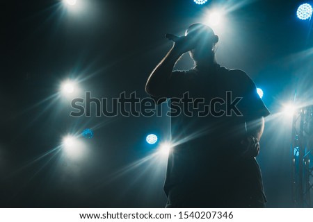 A silhouette of a singer on the stage. Good-looking background, bright stage lights. 