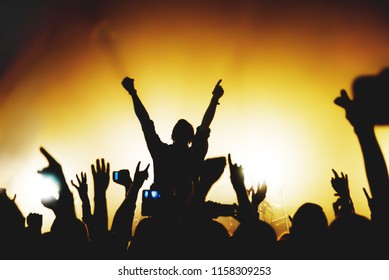 silhouette of a singer performing on stage at a concert among rock fans. the crowd takes pictures of the concert on the phone.  - Powered by Shutterstock