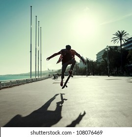 Silhouette of Skateboarder jumping in city on background of promenade and sea - Powered by Shutterstock