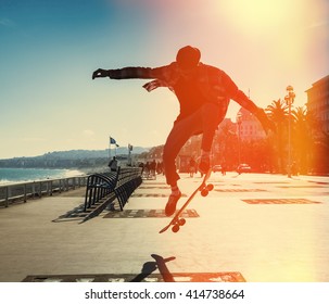 Silhouette of Skateboarder jumping in city on background of promenade and sea - Powered by Shutterstock