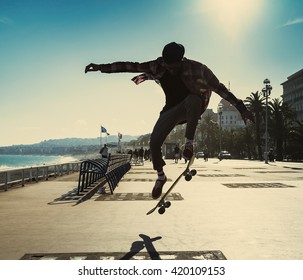 Silhouette of Skateboarder jumping in city on background of promenade and sea - Powered by Shutterstock