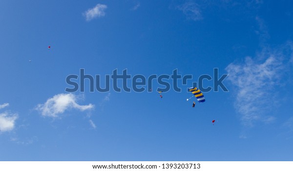 Silhouette of sky divers\
flies back to the ground after a tandem skydive, byron bay,\
queensland,\
australia