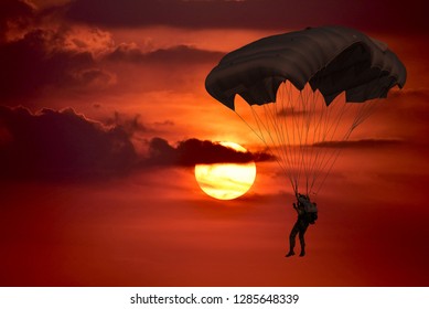 Silhouette skydiver control with  parachute in sunset  sky background with dark cloudy.