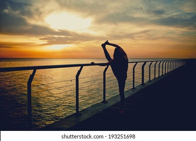 silhouette of a slender woman doing yoga on the sea with a beautiful sunrise - Shutterstock ID 193251698