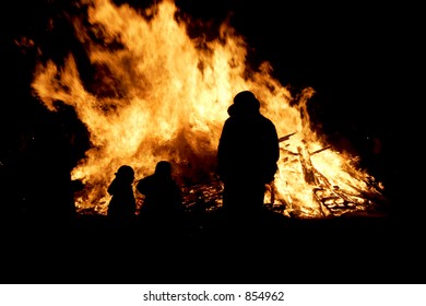 Silhouette, Of A Small Family In Front Of A Bonfire