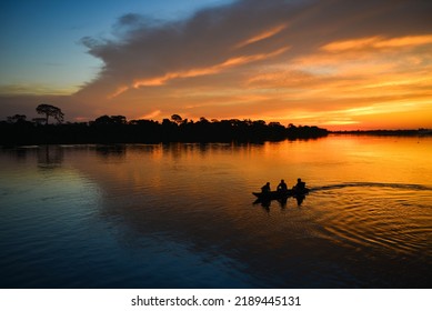 The silhouette of a small motorized canoe on the Guaporé - Itenez river at dusk, Ricardo Franco village, Vale do Guaporé Indigenous Land, Rondonia, Brazil, on the border with Bolivia - Powered by Shutterstock