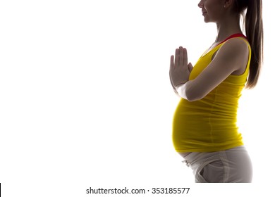 Silhouette of smiling young pregnant fitness model in sportswear doing yoga, pilates training, holding palms in prayer gesture, white background, studio, copy space, isolated, close-up