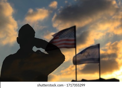 Silhouette Of A Soldier Against The Backdrop Of The US Flag And The Flag Of Israel. Soldier Silhouette In Army Uniform Salutes Friendship And Alliance Of The USA And Israel