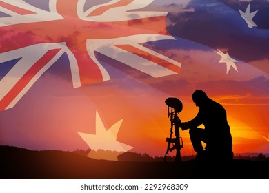 Silhouette of soldier kneeling with his head bowed against the sunrise or sunset and Australia flag. Anzac Day. Remembrance Day. - Powered by Shutterstock