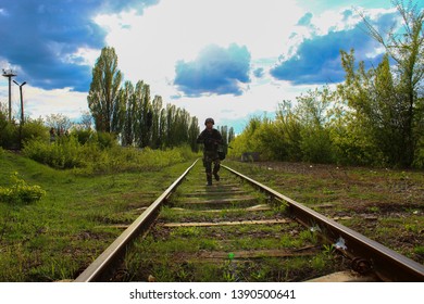 The Silhouette Of A Soldier Walking By Rail In The Overexposed Backlight Of The Sun. Lifestyle