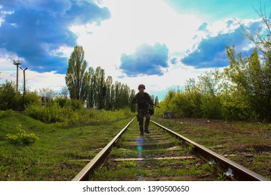 The Silhouette Of A Soldier Walking By Rail In The Overexposed Backlight Of The Sun. Lifestyle