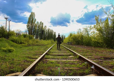 The Silhouette Of A Soldier Walking By Rail In The Overexposed Backlight Of The Sun. Lifestyle