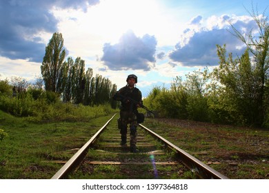 The Silhouette Of A Soldier Walking By Rail In The Overexposed Backlight Of The Sun. Lifestyle