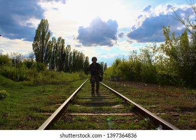 The Silhouette Of A Soldier Walking By Rail In The Overexposed Backlight Of The Sun. Lifestyle