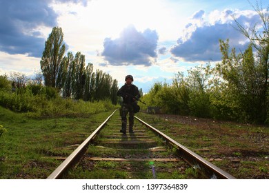 The Silhouette Of A Soldier Walking By Rail In The Overexposed Backlight Of The Sun. Lifestyle