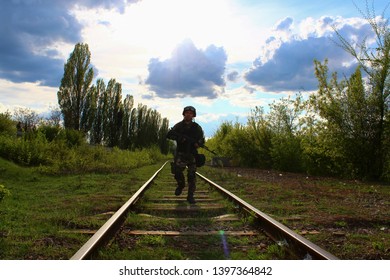 The Silhouette Of A Soldier Walking By Rail In The Overexposed Backlight Of The Sun. Lifestyle