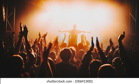 Silhouette Of The Soloist / Vocalist Stands In A Fog In The Rays Of Light. Concert Crowd In Front Of Bright Stage Lights. Dark Background, Smoke, Concert  Spotlights