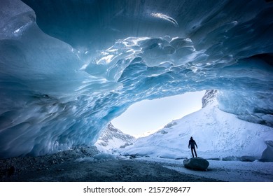Silhouette of someone standing on a rock while exploring an ice cave in Zinal glacier, Valais Switzerland