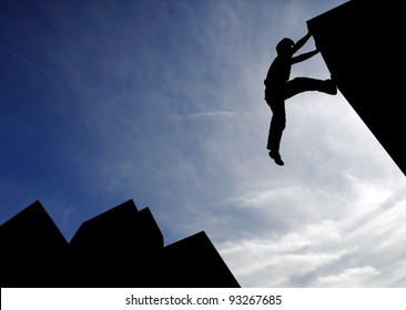 Silhouette of a sport boy scaling a wall in an urban surrounding against a blue cloudy sky for the concept of urban playground. - Powered by Shutterstock