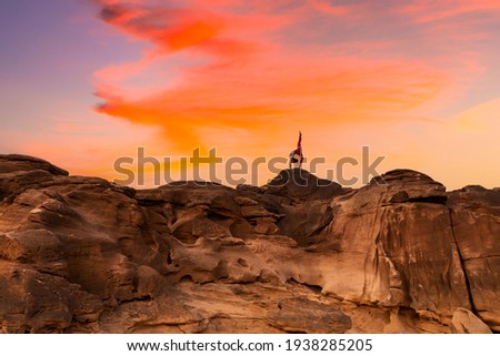 Silhouette sport woman practice asana  meditation flexibility sport healthy concept playing outdoor on high rock with beautiful sun sky background.