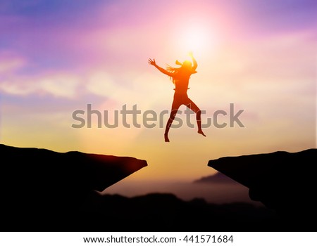 Silhouette Sports Woman to jump over obstacles over precipice between two rocky mountains over blurry background sunset.concept Freedom. Risk for a challenge success. Be a different business