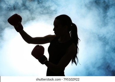 Silhouette of strong boxer woman on dark background - Powered by Shutterstock