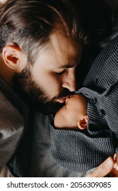 Silhouette Of A Stylish Bearded Father Kisses A Sleeping Newborn Girl. Parent Holding Rocking Child Daughter Son In Hands. Authentic Lifestyle Parenting Fatherhood Moment. Single Dad Family Home Life.