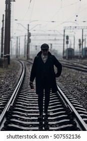 silhouette of stylish man in retro look walking in rain on background of foggy railway. england in 1920s theme. fashionable brutal gangster. atmospheric  moments. space for text