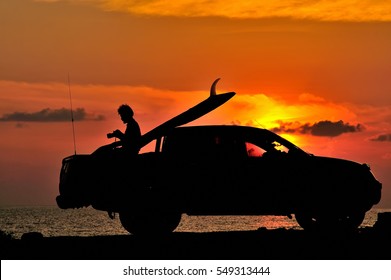 The Silhouette Of A Surfer  And Car  During Sunrise On The Beach