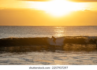 Silhouette surfer catching a wave at sunrise - Shutterstock ID 2257937297