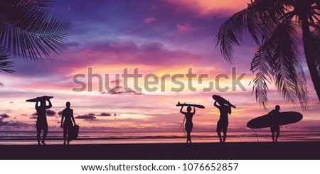 Silhouette of surfer people carrying their surfboards on sunset beach. Panoramic soft style with vintage filter effect for banner background. 