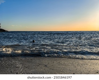 Silhouette of a swimmer swiming in a sunset at a beautiful Gortan bay in Adriatic sea in Pula Croatia. Blue sea and sky, sand beach and rocks - Powered by Shutterstock