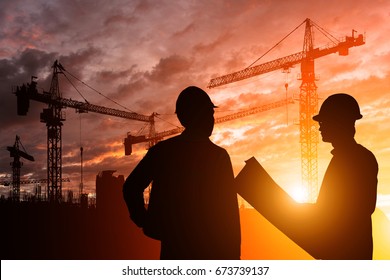 Silhouette Teams engineer looking construction worker in a building site at sunset