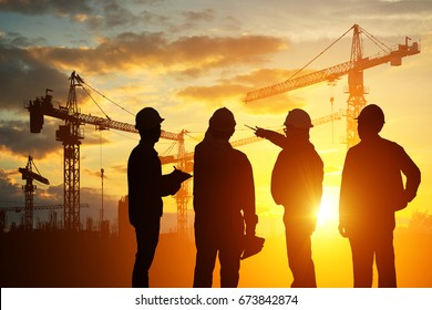 Silhouette Teams engineer looking construction worker in a building site at sunset