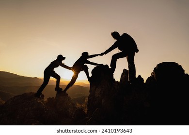 silhouette of Teamwork of three  hiker helping each other on top of mountain climbing team. Teamwork friendship hiking help each other trust assistance silhouette in mountains, sunrise.  - Powered by Shutterstock