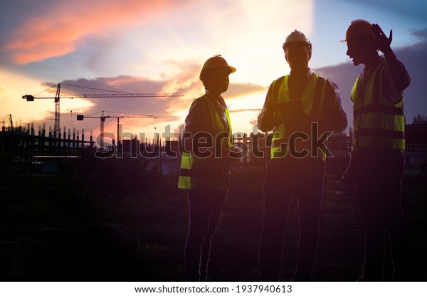 Silhouette of Teamwork, worker in uniform and\
wearing safety helmet while working on commercial dock site with\
container box from cargo freight ship for import export. industry\
factory worker.