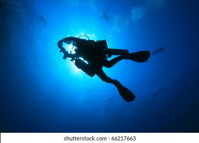 Silhouette of a Technical Scuba Diver carrying extra cylinders, returning from a deep exploration dive